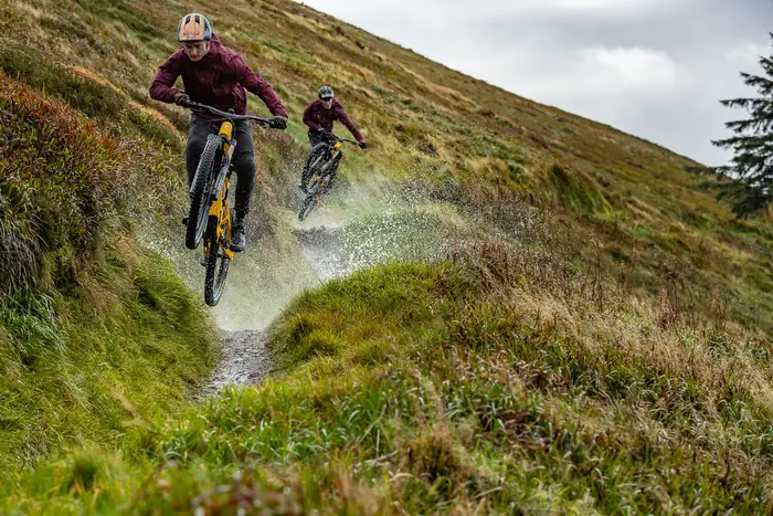 Two mountain bikers splashing through a wet trail on the Rostrevor Mountain Bike Trails
